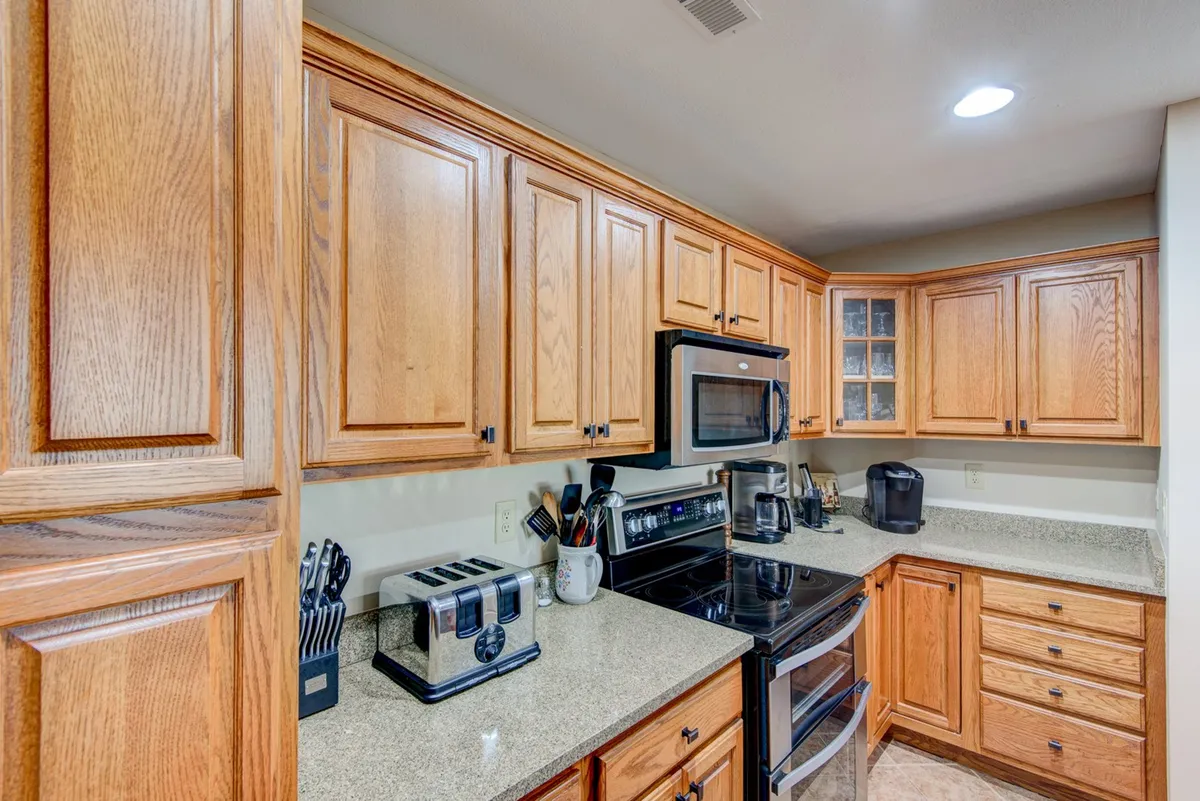 A modern kitchen with wooden cabinets, gleaming granite countertops, stainless steel appliances, and essential kitchenware. The space is set up for both cooking and entertaining, inviting you to linger over breakfast or prepare meals together.