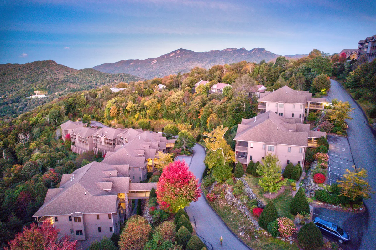 This exterior image features a scenic road winding through vibrant, colorful trees with a majestic mountain backdrop. The well-maintained landscaping adds charm, and the natural beauty highlights the ever-changing seasons of the High Country. The image evokes a sense of adventure and exploration, inviting viewers to imagine exploring the surrounding area.