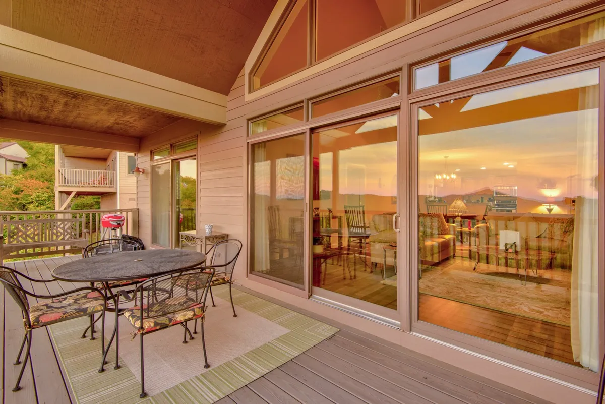 An exterior dining area situated just outside large windows, with a table and chairs arranged for al fresco meals. The seating area provides uninterrupted views of the mountains and a dramatic sunset, inviting guests to linger for evening conversation or a morning coffee while soaking in the landscape.